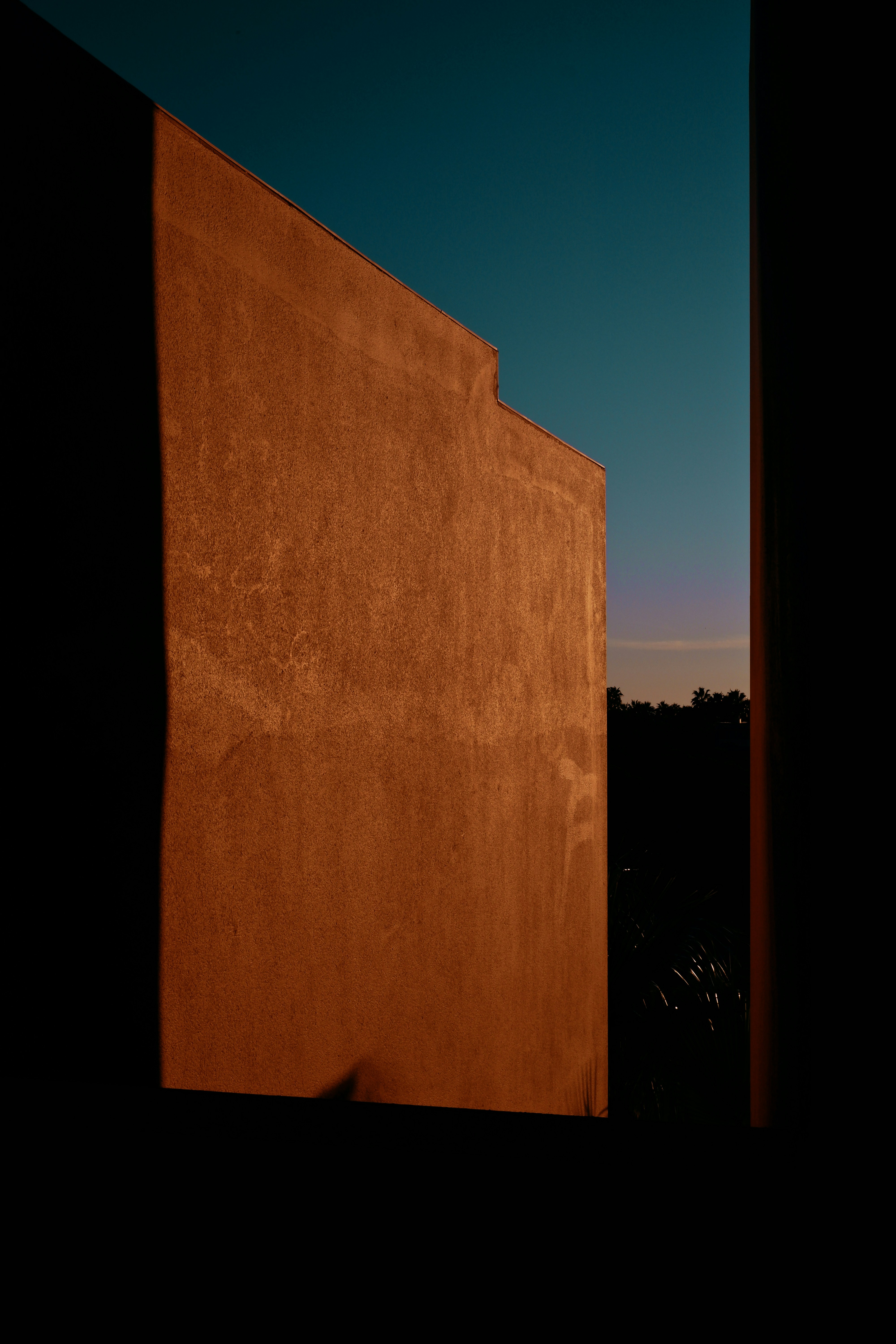 A sunlit clay wall meeting a deepening dusk sky in Phoenix, Arizona.